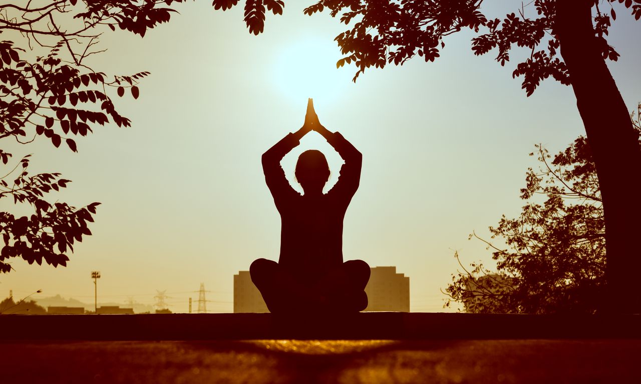 services-01 Silhouette of a person practicing yoga outdoors during sunrise, creating a calming atmosphere.